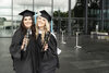 Zwei fröhliche Diplomandinnen im Talar mit dem Diplom in der Hand vor dem Eventlokal
