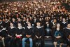 Absolventinnen und Absolventen warten gespannt im grossen Saal sitzend auf die feierliche Diplomübergabe.